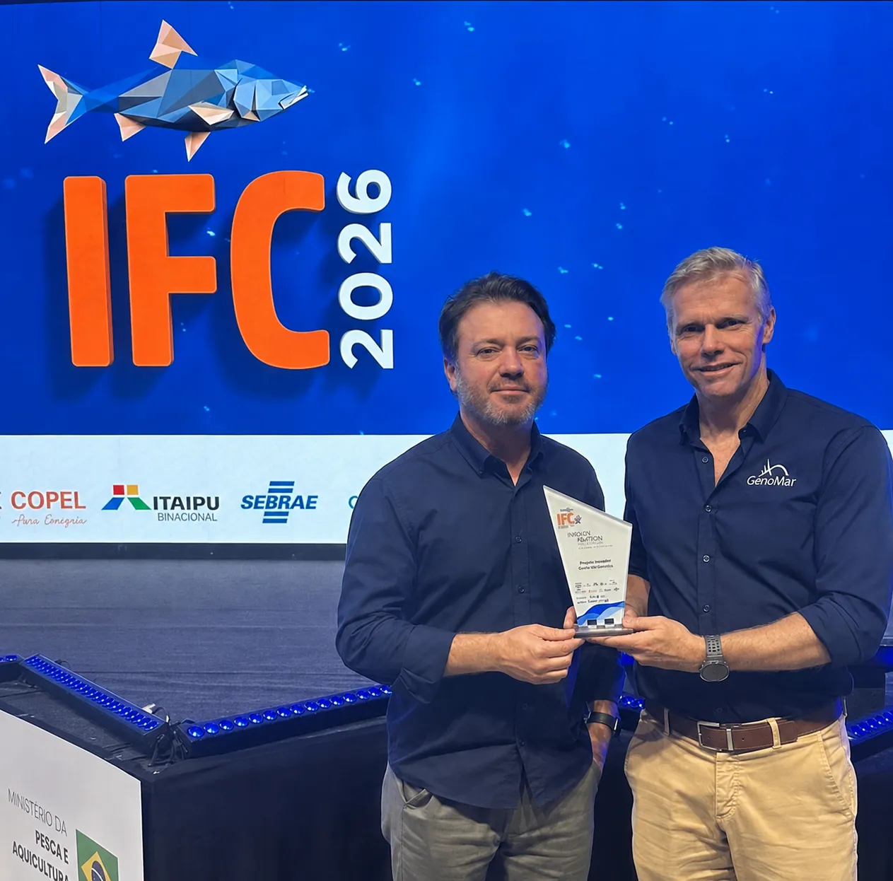 Representantes da GenoMar com o troféu do Prêmio de Inovação na Aquicultura no palco do IFC Brasil 2026