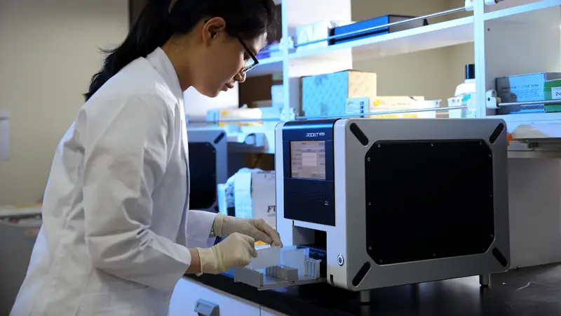 Técnica de laboratório carregando amostras em um equipamento compacto de PCR